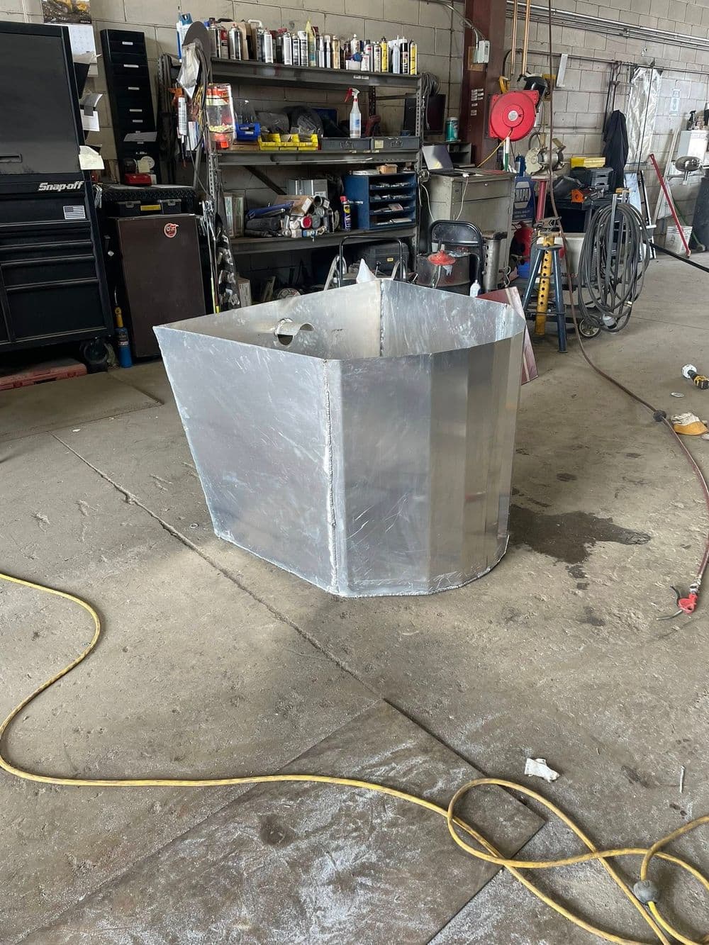 Aluminum fabrication in workshop, showing a partially assembled metal container on the floor.